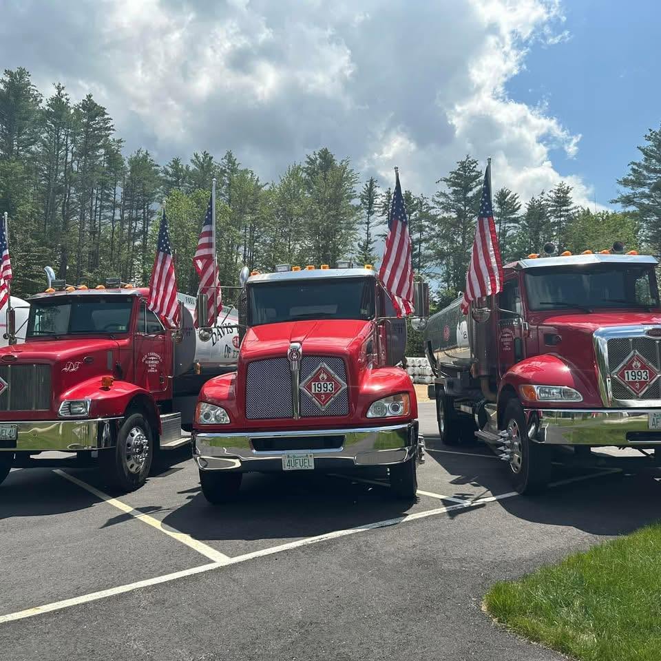 Three red Davis Fuels delivery trucks flying American flags in Epsom